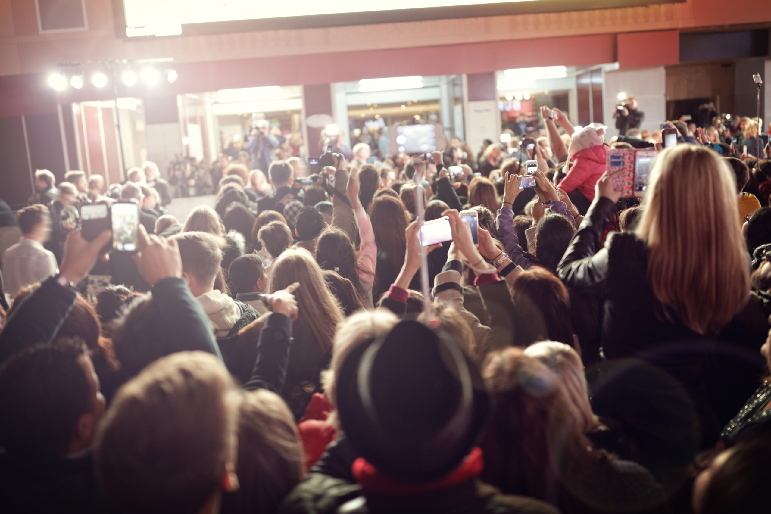 Crowd of people holding smartphones and cameras capturing a celebrity public appearance, symbolising intense media attention and reputational risk.