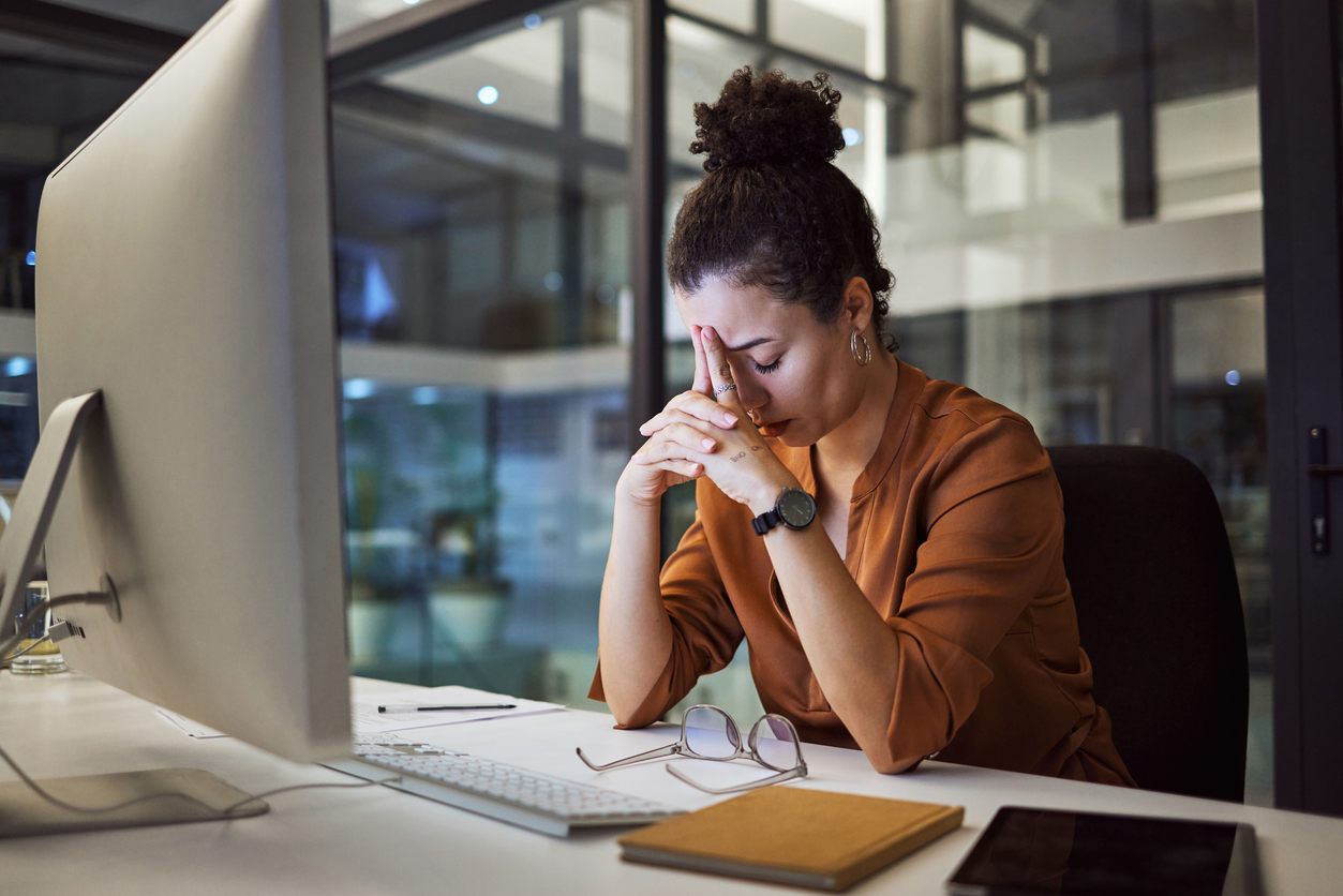 Young professional sitting at her desk looking stressed, representing financial pressure and early career money challenges.