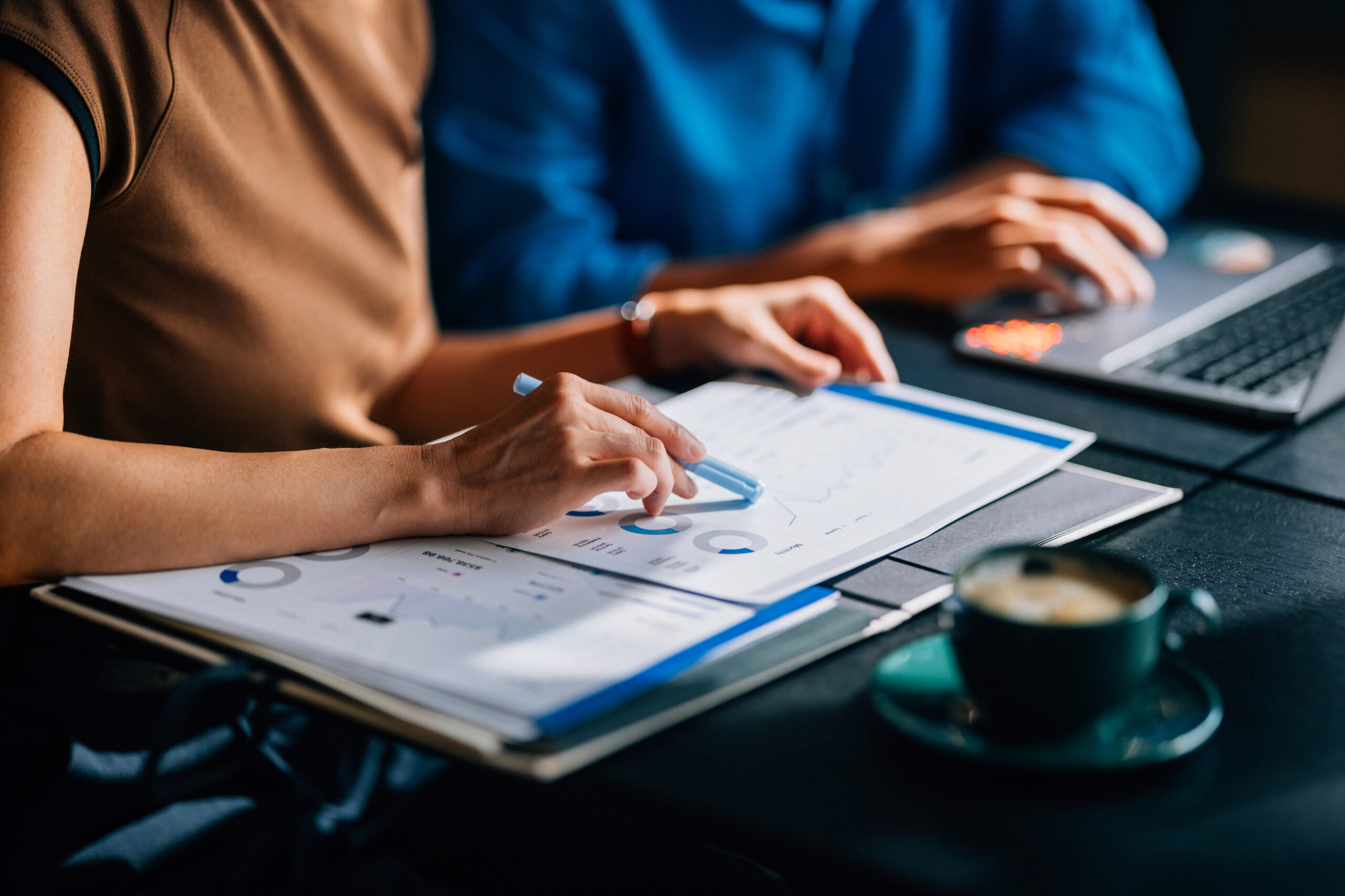 Two professionals reviewing financial charts and documents, representing planning and investing to build assets from salary income.